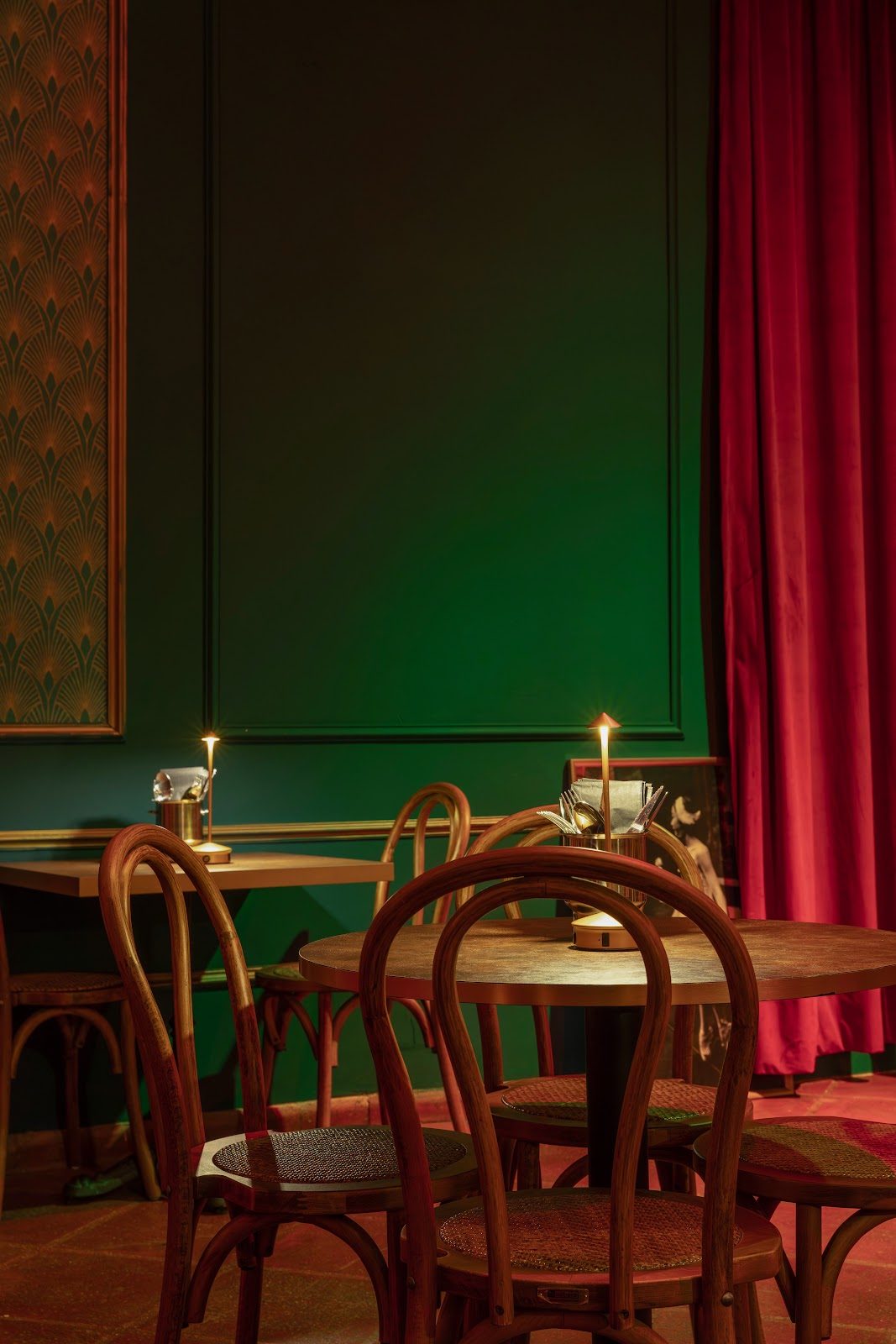 Cozy interior of 021 Back Room featuring wooden tables, chairs, and rich green and red decor.