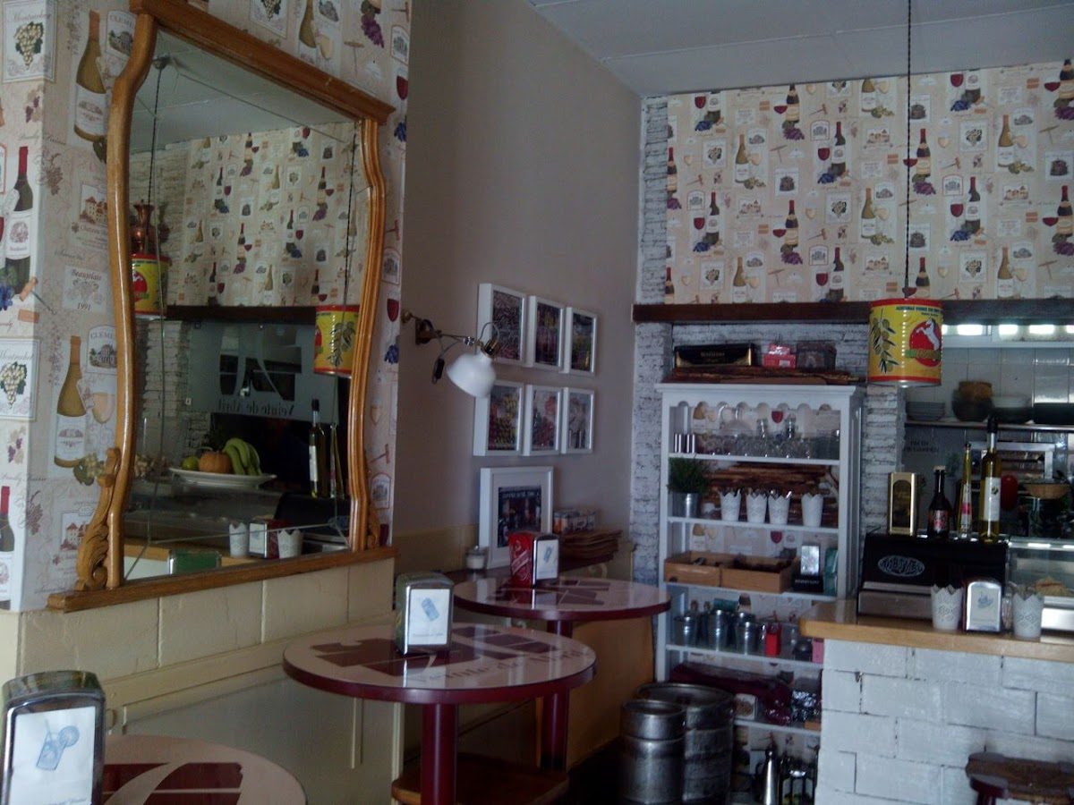 Cozy interior of 20 de Abril featuring wooden tables, decorative wallpaper, and a mirrored wall.