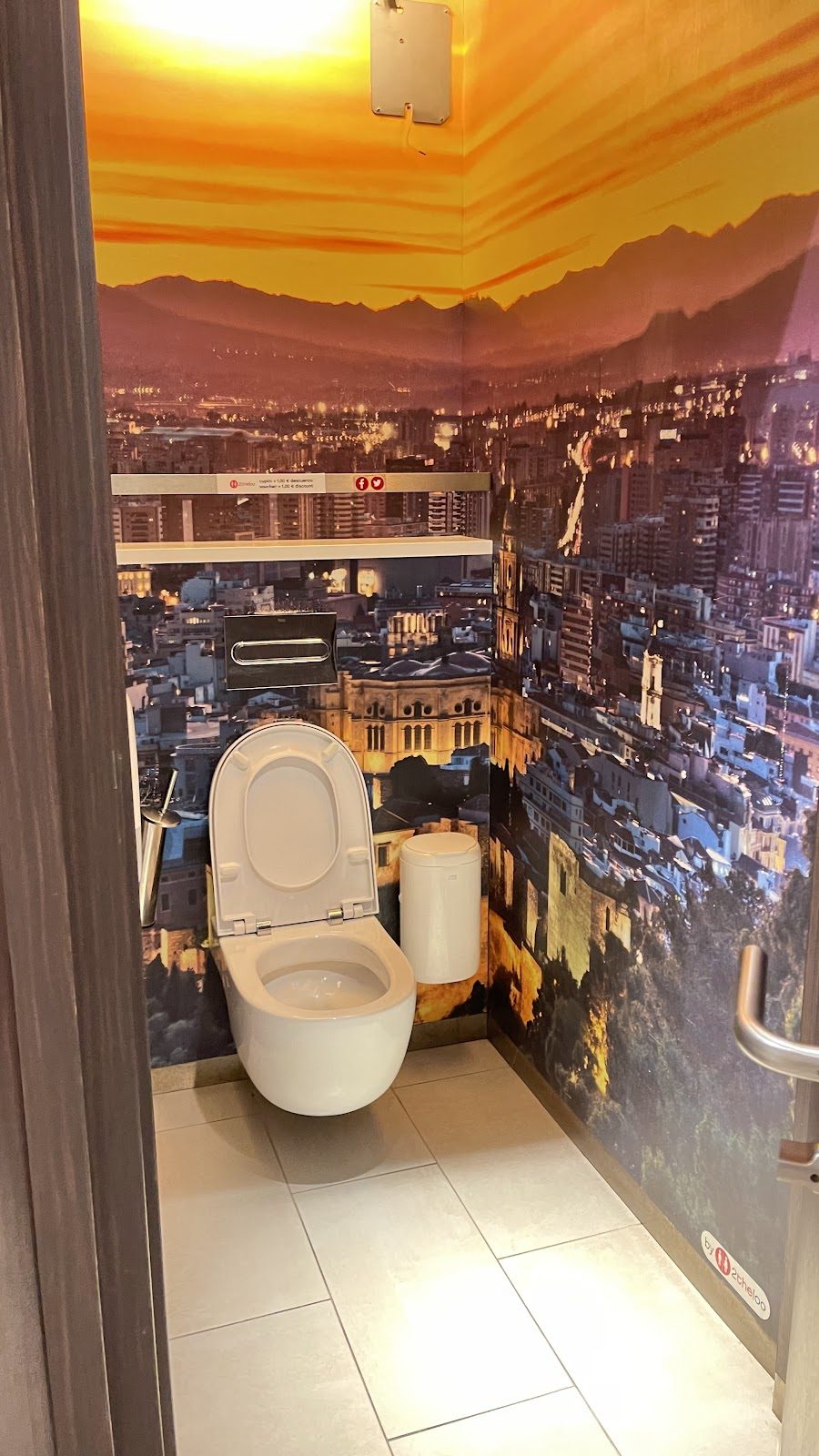 The interior of 2theloo features a toilet with a scenic wall mural of Málaga.