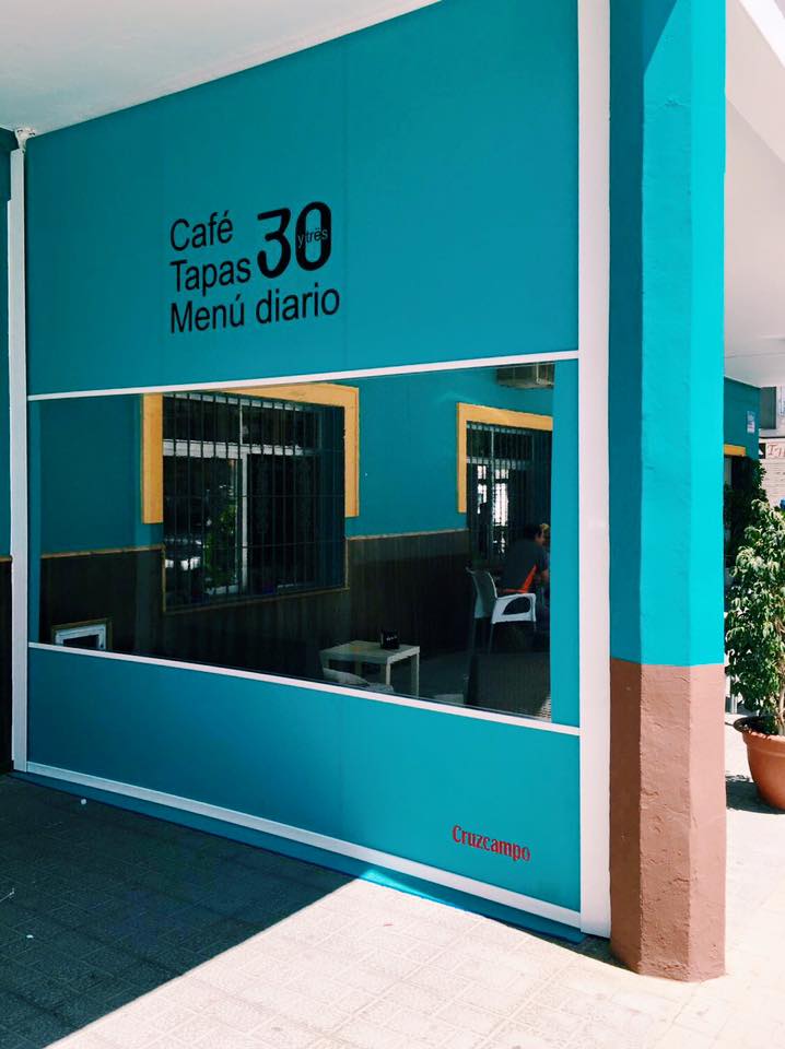 The exterior of 33 café bar features a bright turquoise wall with large signage for café, tapas, and daily menu.