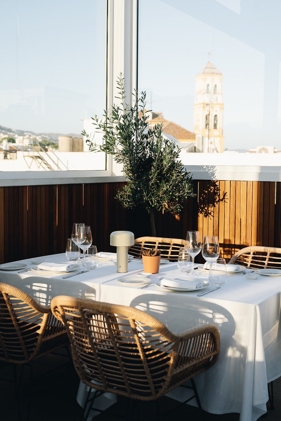 A stylish dining table set with glasses and a plant, overlooking a scenic view at 360 Blue Sky bar.