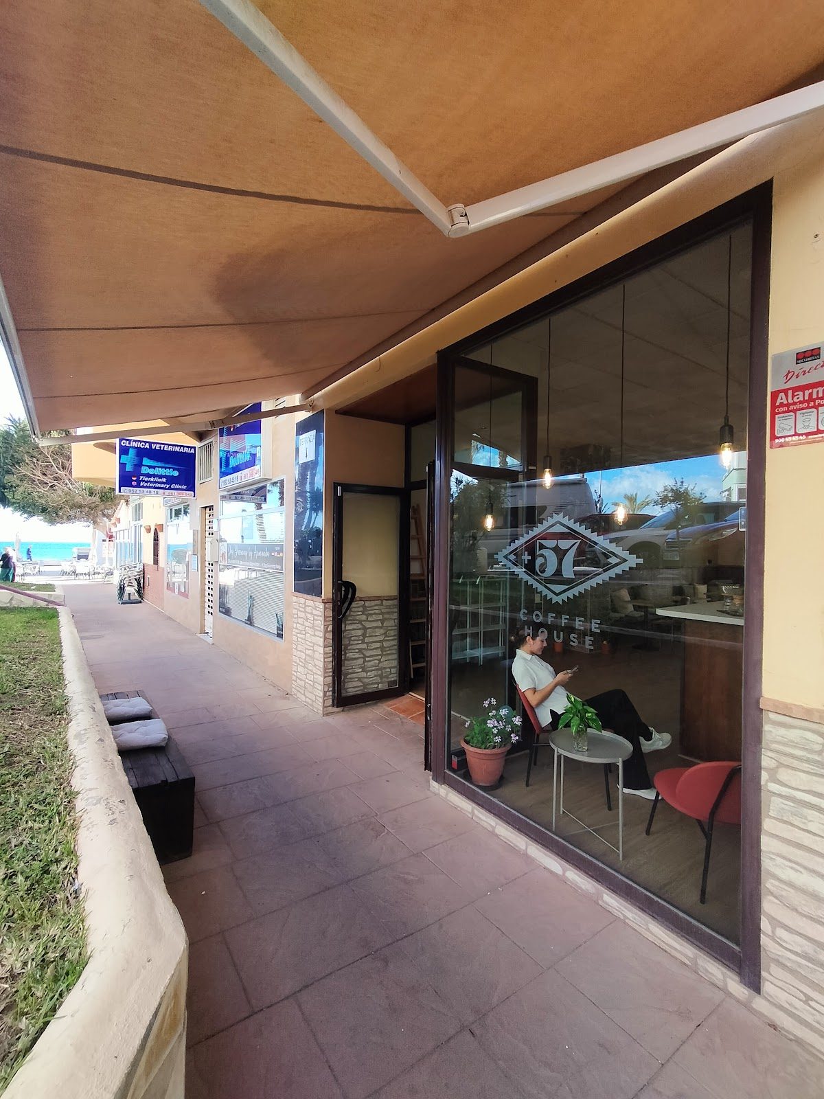 The exterior of +57 Coffee House features large windows, outdoor seating, and a modern design.