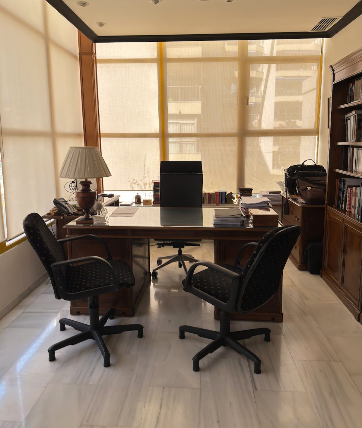 The office of Abogados - Herrera y Abalos features a wooden desk, two chairs, and large windows with natural light.
