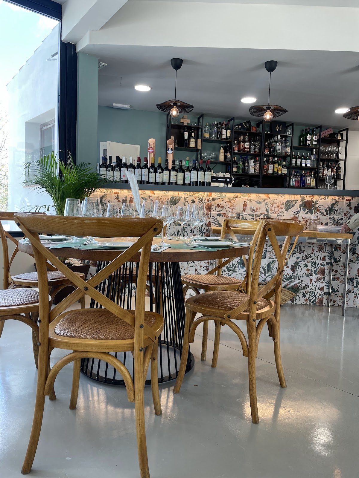 Abrasador El Cortijo La Martina features a modern interior with wooden chairs and a floral bar backdrop.