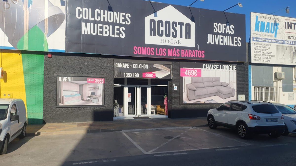 Vista exterior de Acosta Hogar, con coloridos letreros y pancartas promocionales de muebles y colchones.