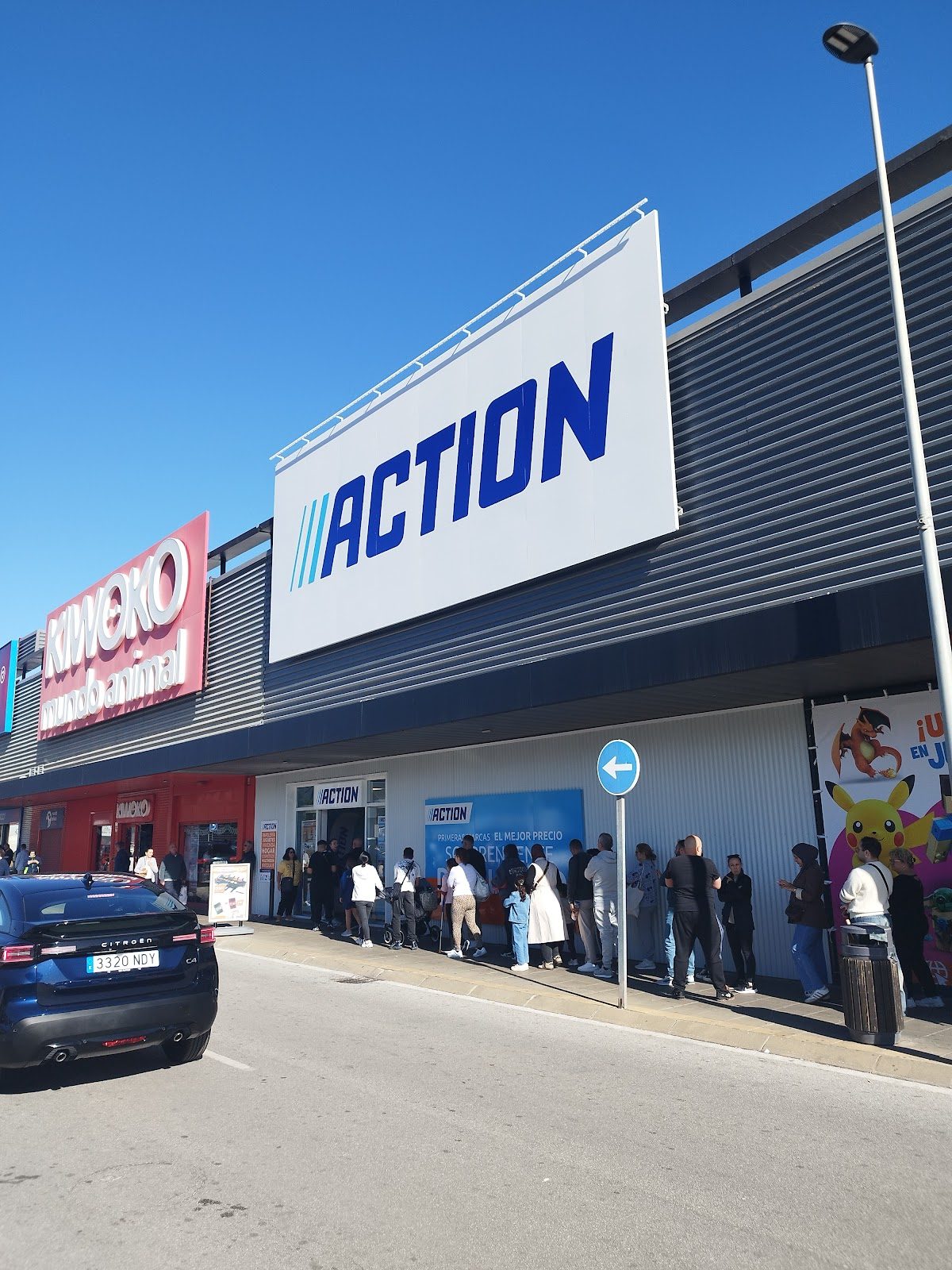 The exterior of Action Málaga features a large sign, with a queue of customers outside the store.