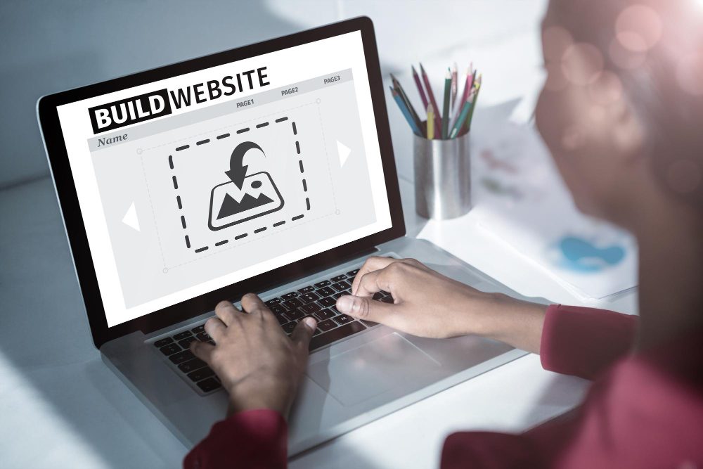 Una persona trabajando en una computadora portátil que muestra la interfaz de diseño del sitio web Adiseñar.