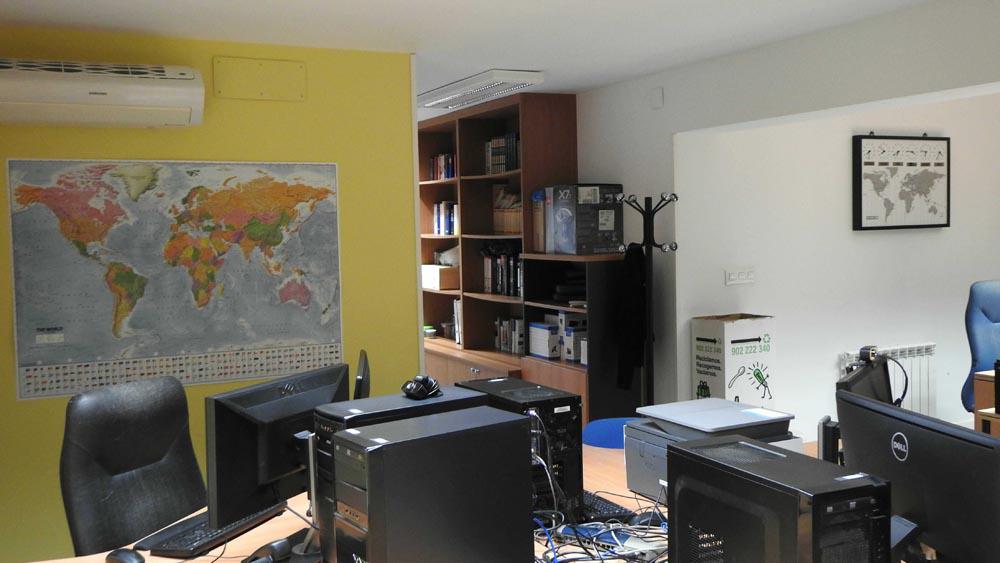 Interior de la oficina de LinguaVox con ordenadores, un mapamundi y estanterías.