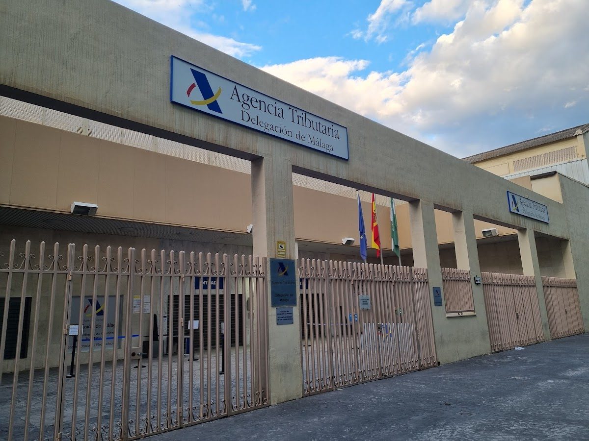 Vista exterior del edificio de la Agencia Tributaria con letreros y banderas en Málaga.