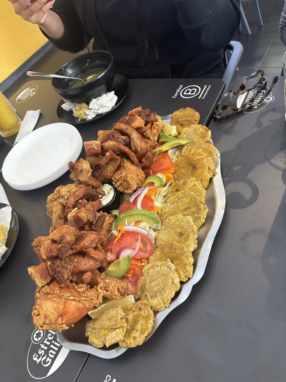 Aguardiente Restaurante - Bar features a large platter with fried chicken, pork, plantains, and fresh vegetables.