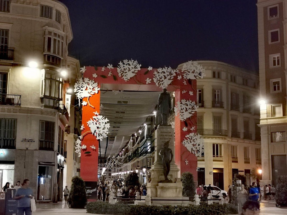 A vibrant night scene at Alameda Principal - Norte with decorative archways and people strolling.