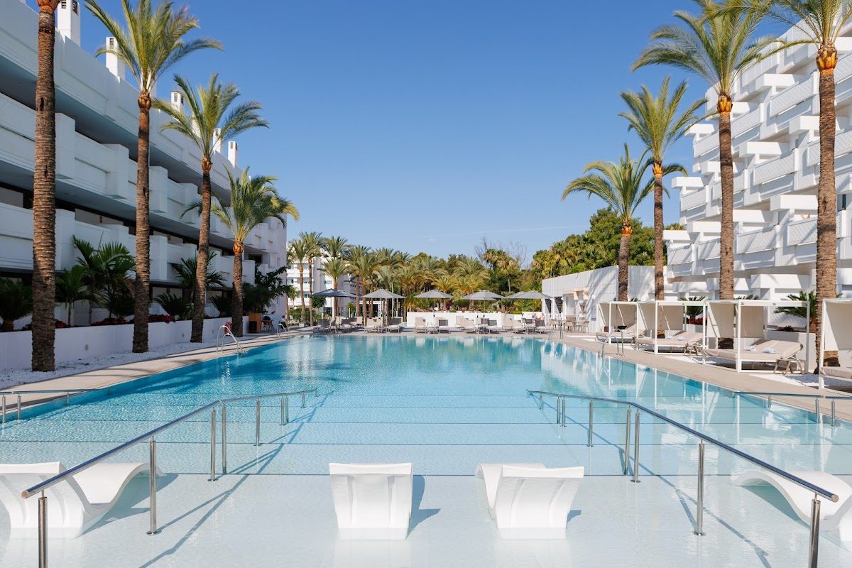 El Hotel Alanda Marbella cuenta con una amplia piscina al aire libre rodeada de palmeras y tumbonas.