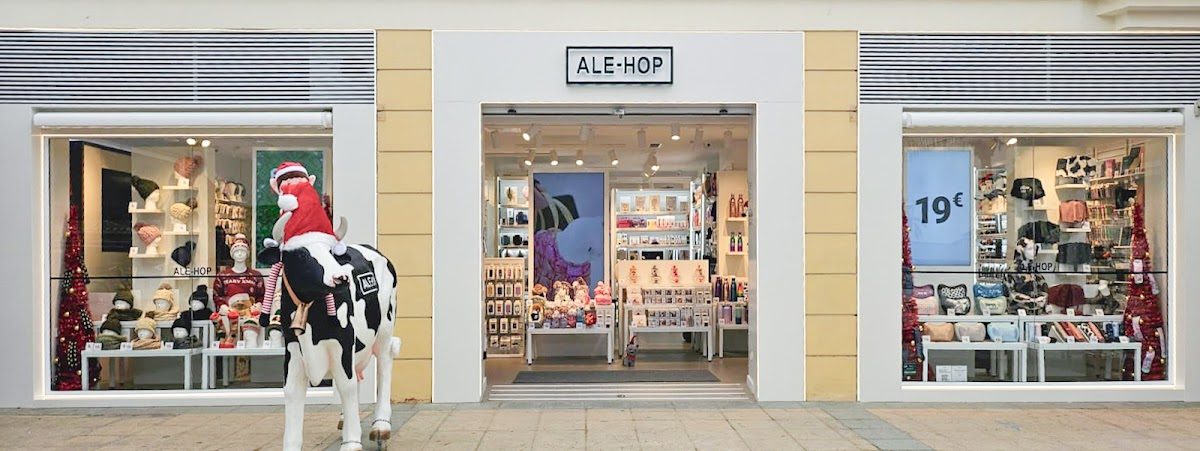 The ALE-HOP store features colorful merchandise displays and a cow statue dressed as Santa outside.