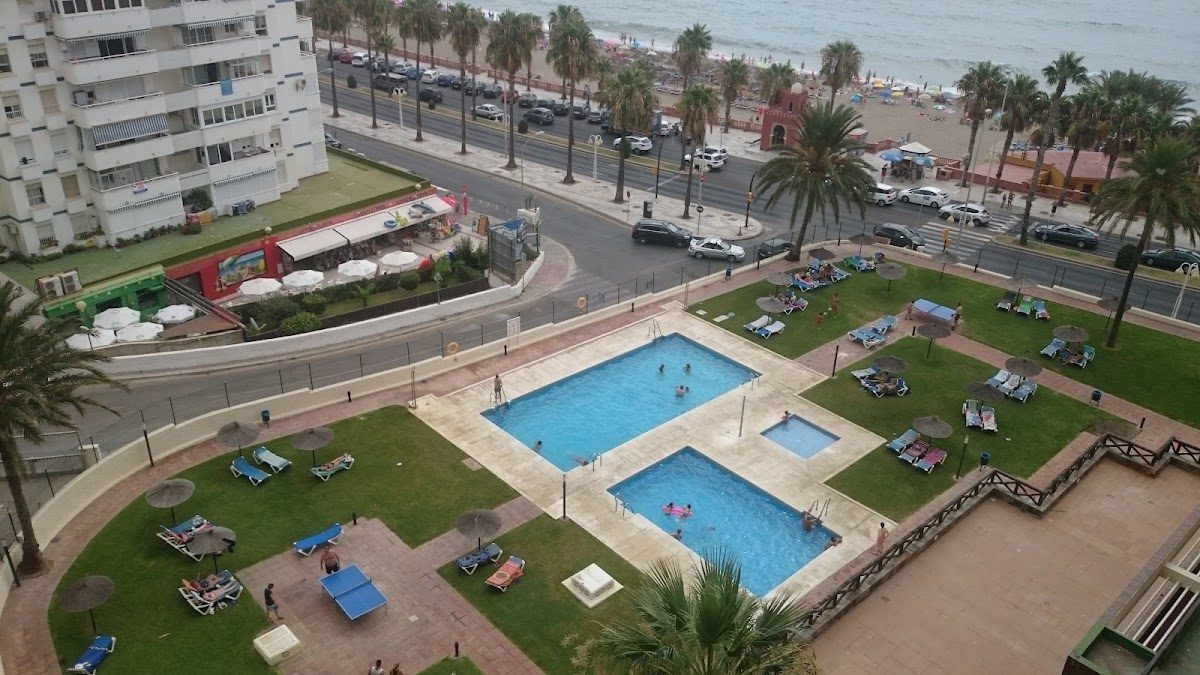 Aloha Playa cuenta con piscinas al aire libre rodeadas de palmeras y tumbonas, con vistas a la playa.