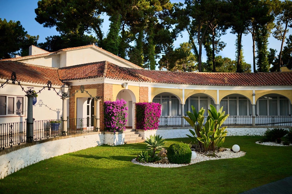 Vista exterior del parque AluaSun Marbella, con jardines paisajísticos y vibrantes flores moradas.