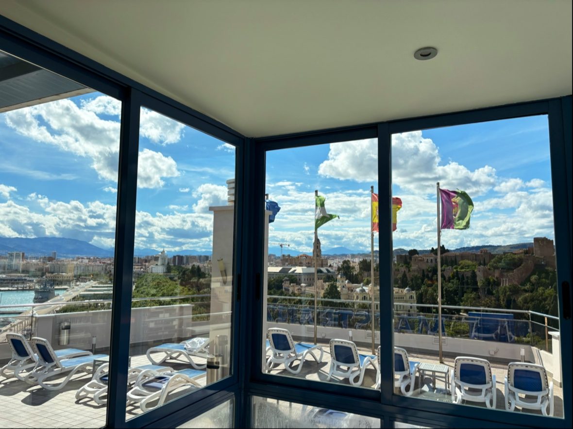 Vista desde Alum Spa Maestranza mostrando banderas y un cielo soleado sobre Málaga.