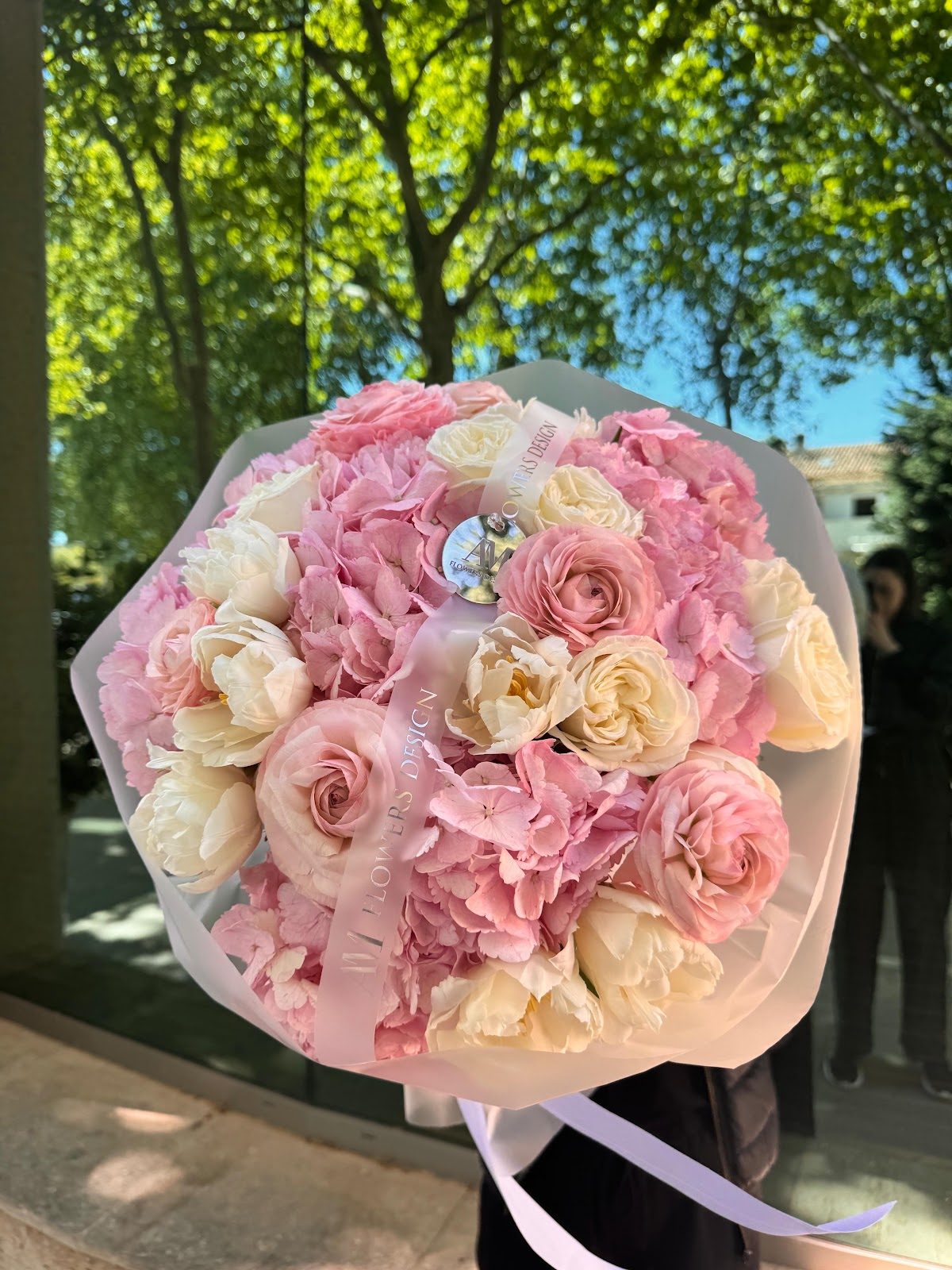 Un ramo compuesto por rosas rosas y blancas e hortensias, elegantemente envuelto con una cinta.
