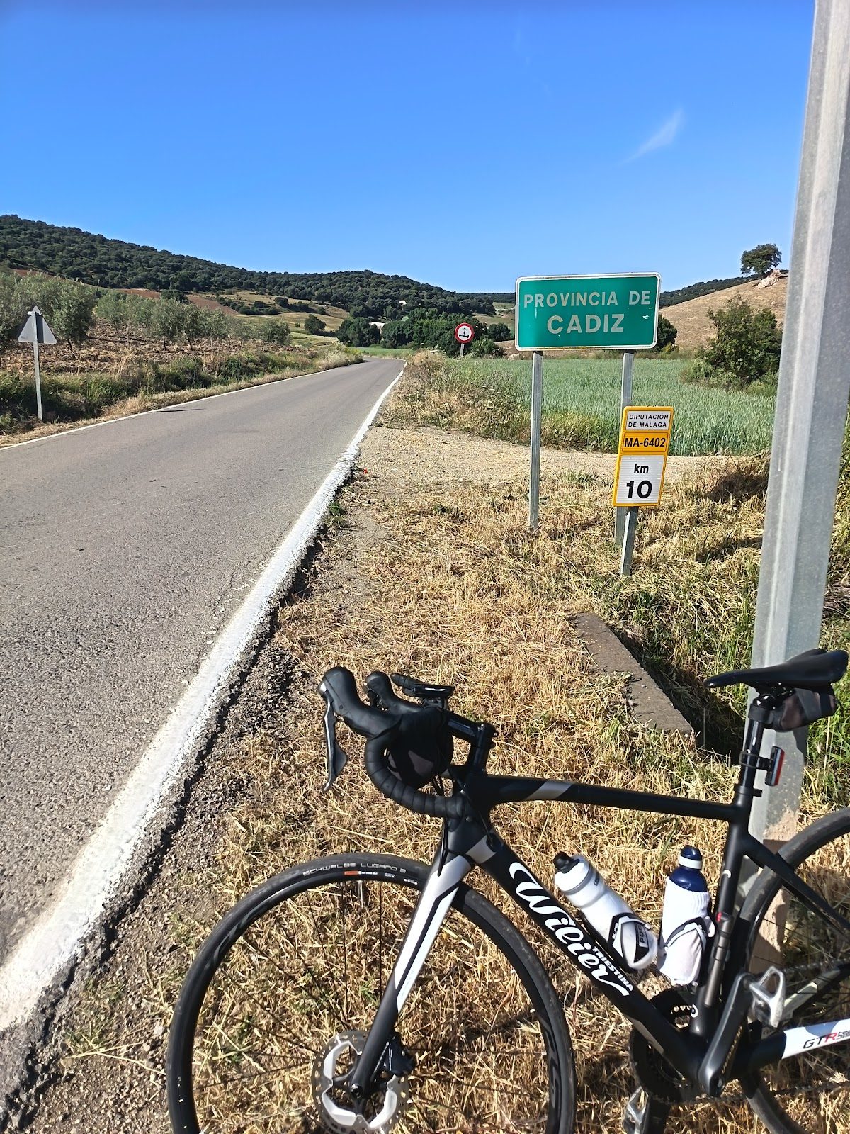 A road sign indicating the border of Cádiz province with a bicycle parked nearby.