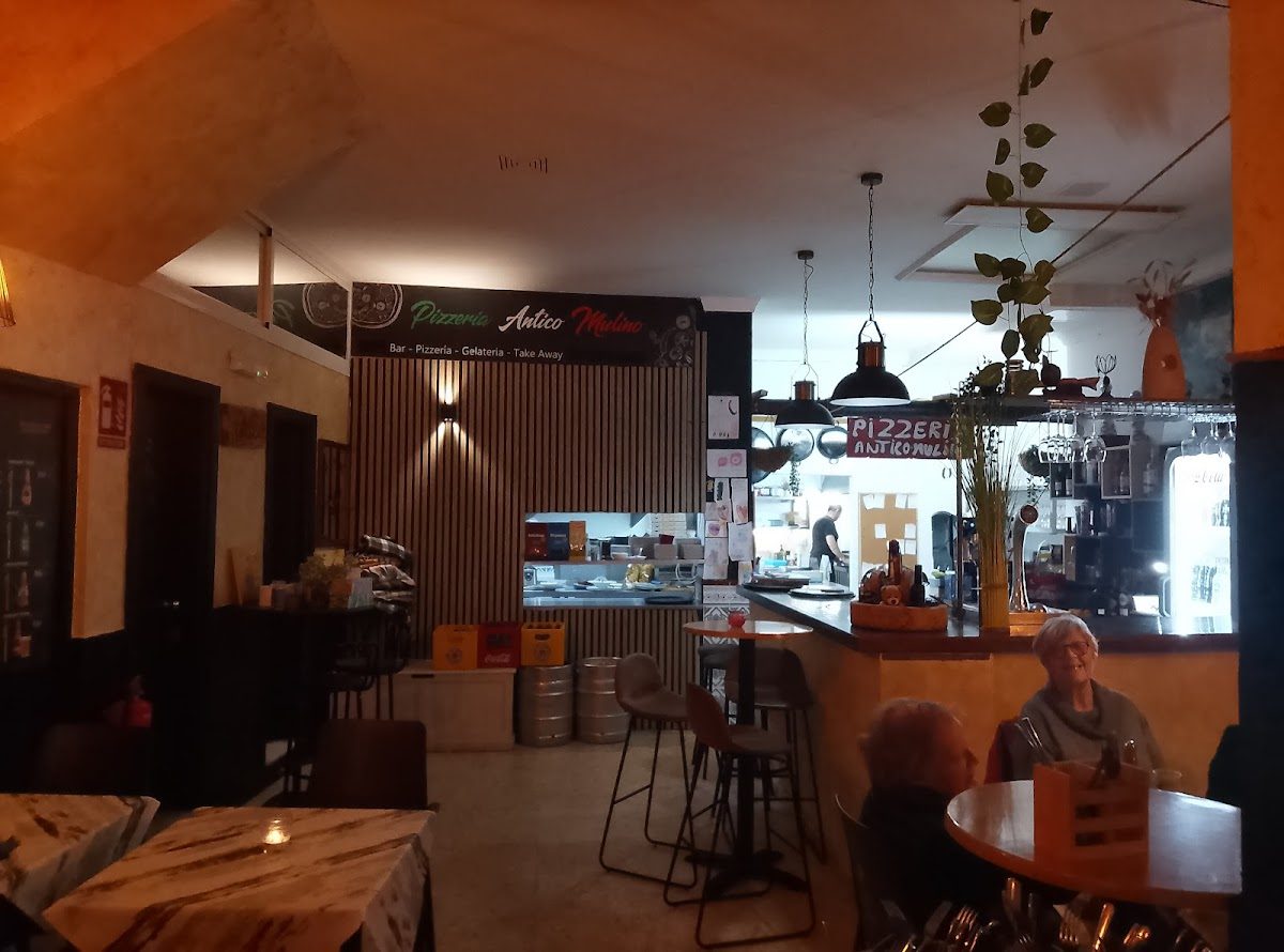Interior view of Antico Mulino Pizzeria featuring a bar area and seating for customers.