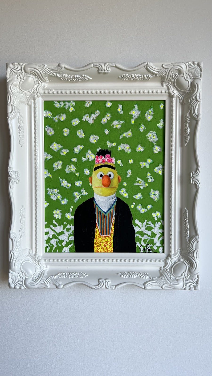 Un colorido cuadro enmarcado de un personaje con un fondo floral, expuesto en una pared.