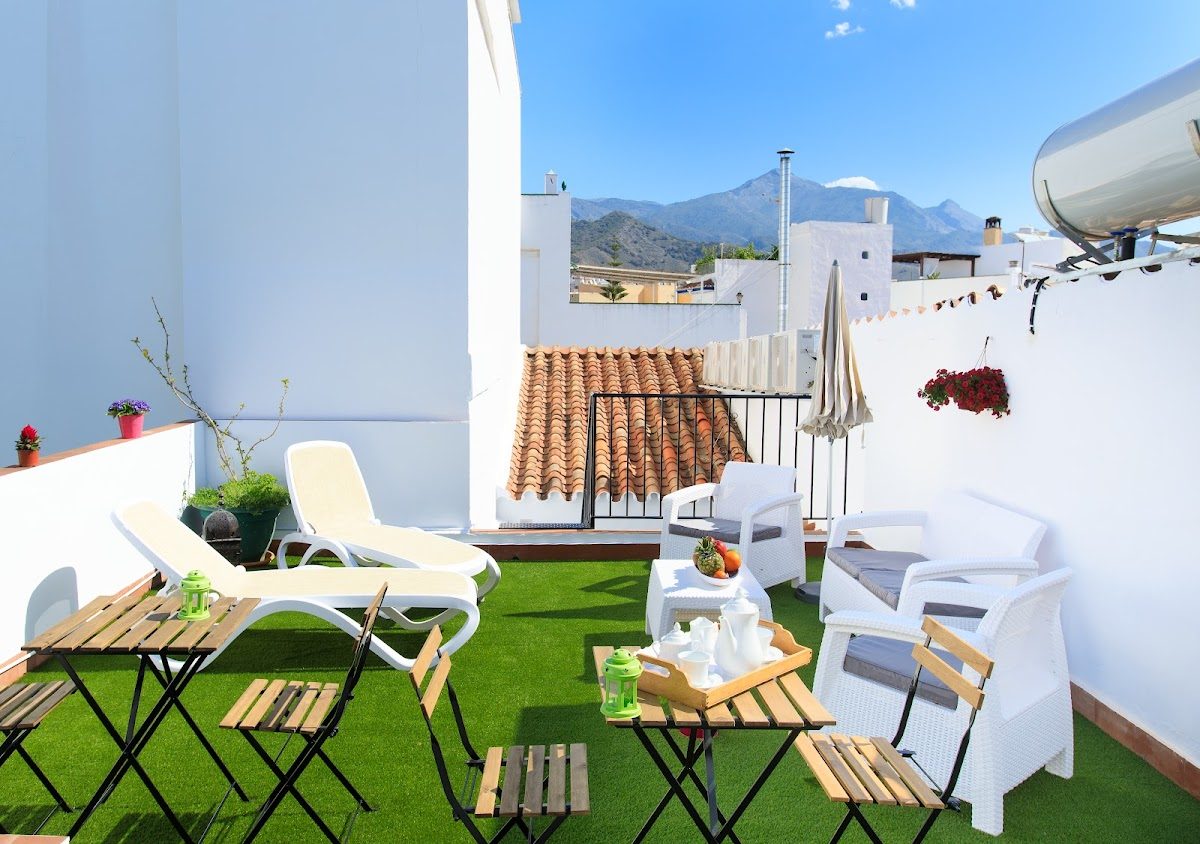 Rooftop terrace at Armijorooms Guesthouse Nerja with lounge chairs and mountain views.