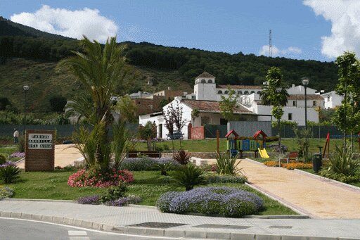 El parque Arquilla del Agua cuenta con coloridos juegos infantiles rodeados de jardines paisajísticos y montañas al fondo.