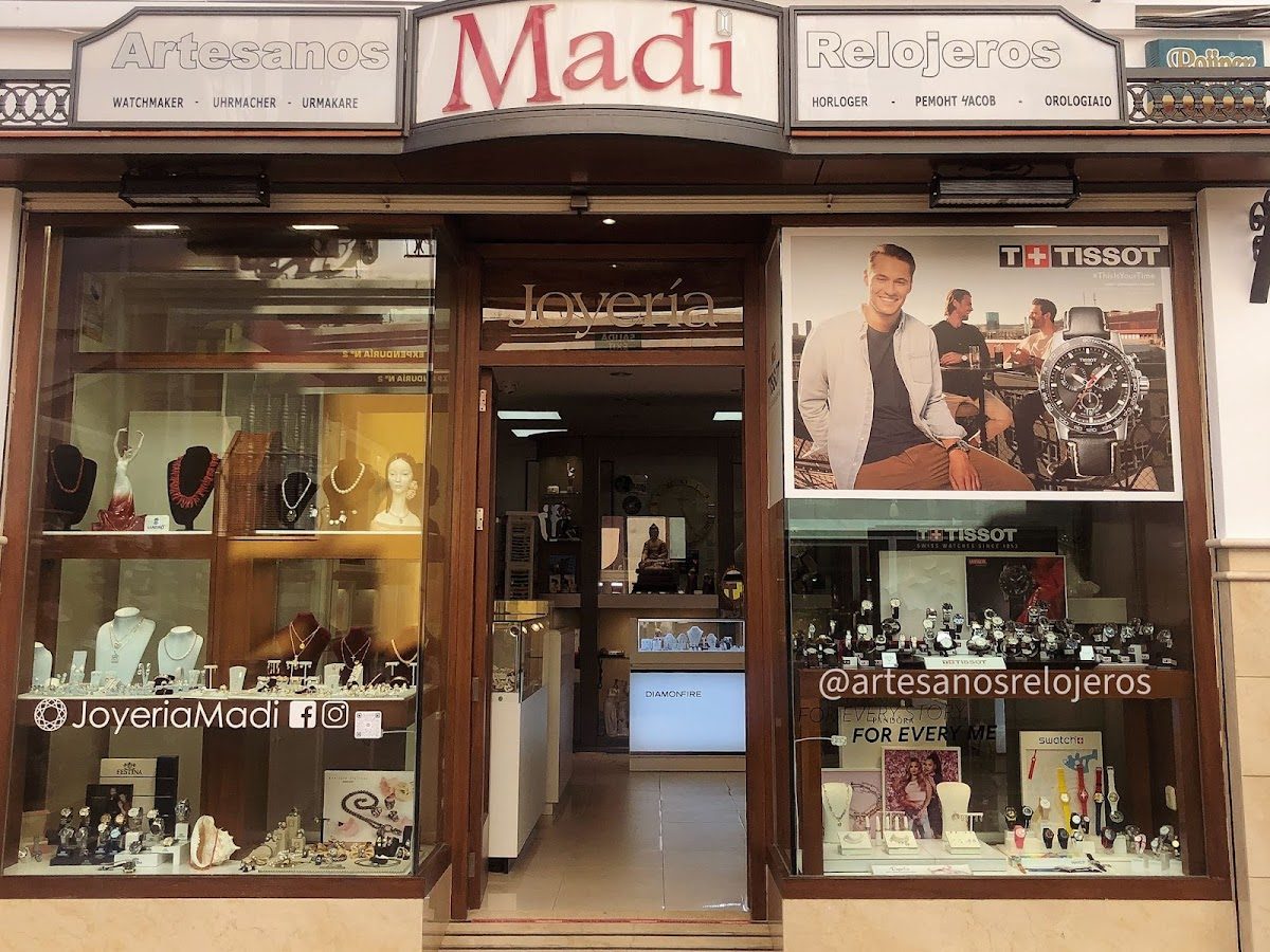 The storefront of Artesanos Relojeros features jewelry displays and a large Tissot advertisement.