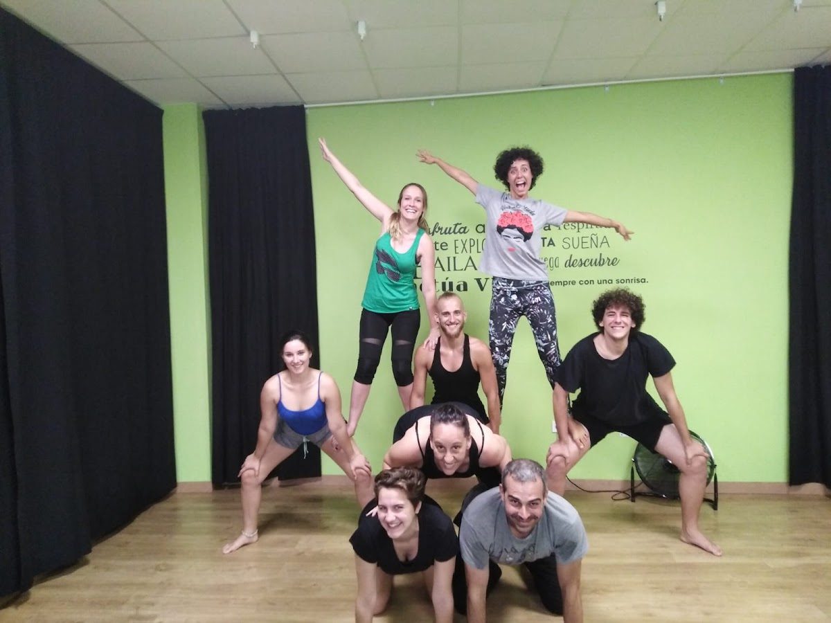 Un grupo de personas formando una pirámide humana en un estudio de color verde brillante en Artístika.