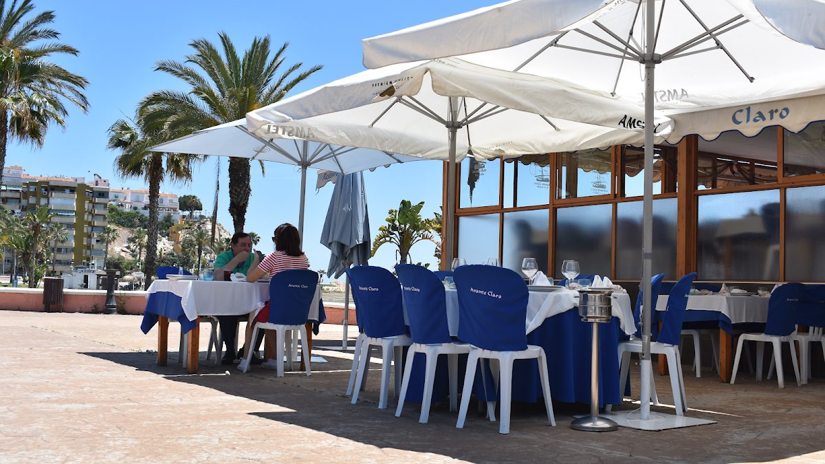 Terraza exterior del restaurante Avante Claro, con mesas, sillas y palmeras, en La Cala del Moral.