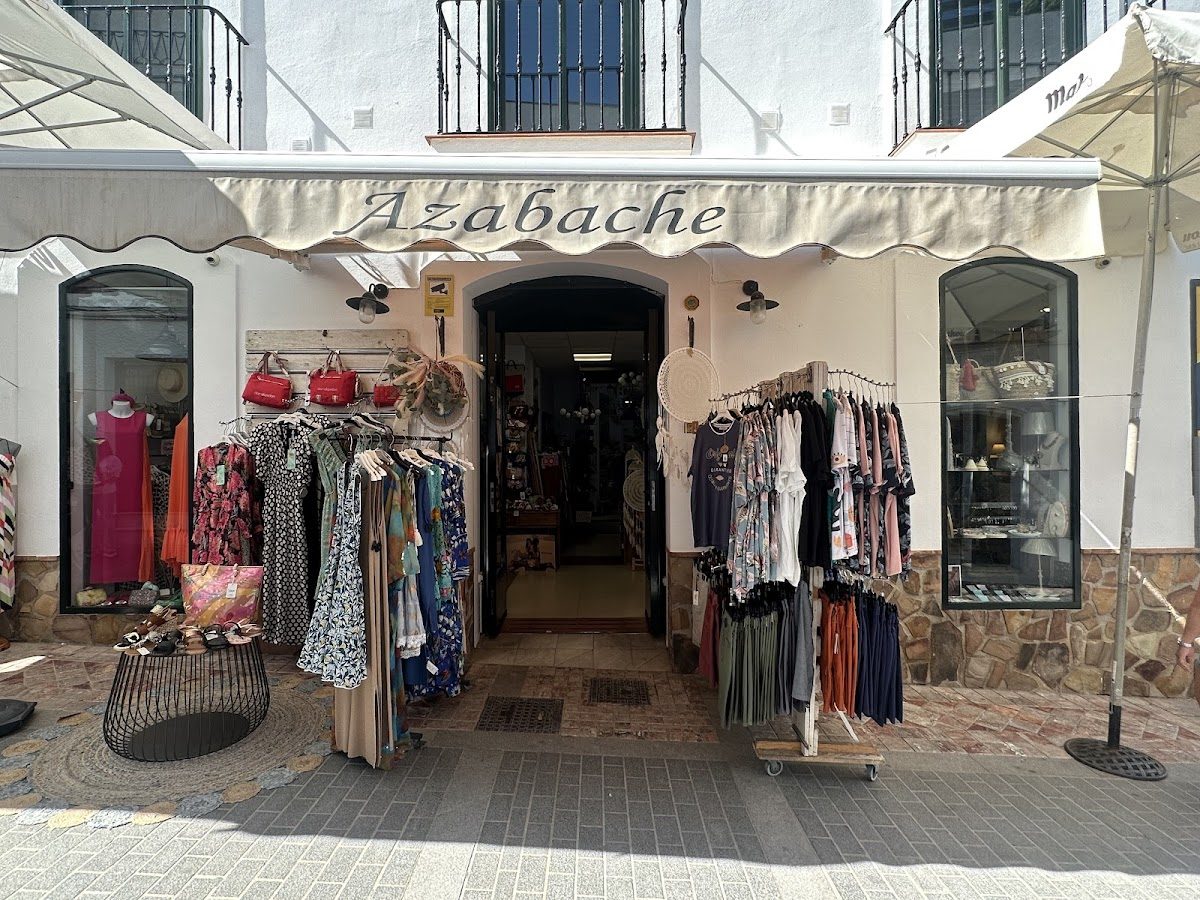 The entrance of Azabache features a variety of clothing displayed outside under a stylish awning.