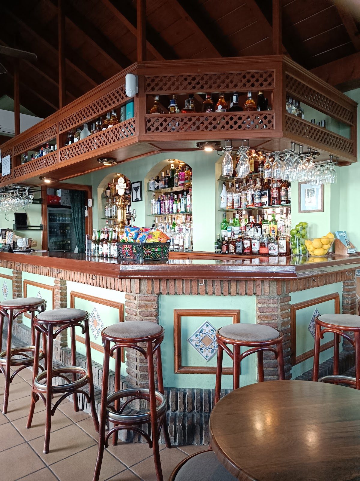 Bar Hemingway's features a wooden bar with a variety of spirits and seating at high stools.