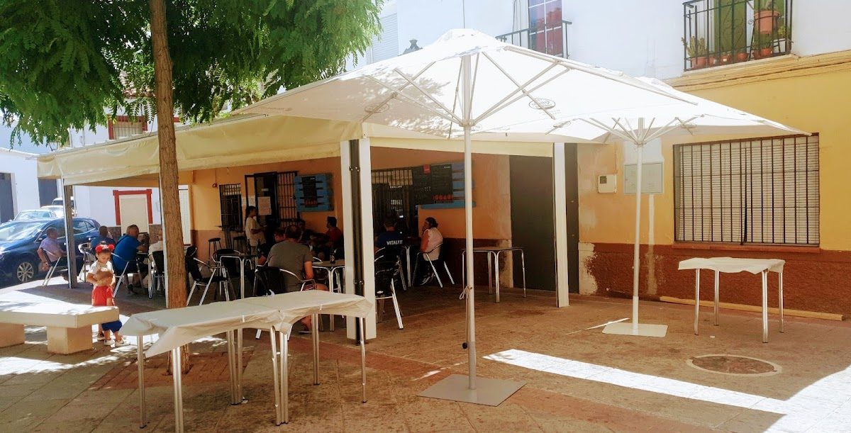 Bar Linares features outdoor seating with umbrellas in a plaza, surrounded by trees and a relaxed atmosphere.