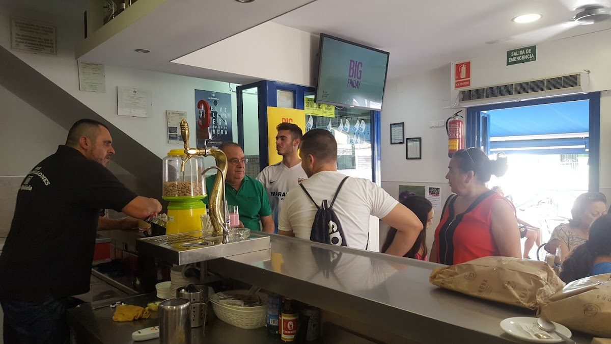 El bar Los Almellones tiene un interior muy animado, con clientes en la barra y en las mesas, y un barista sirviendo bebidas.