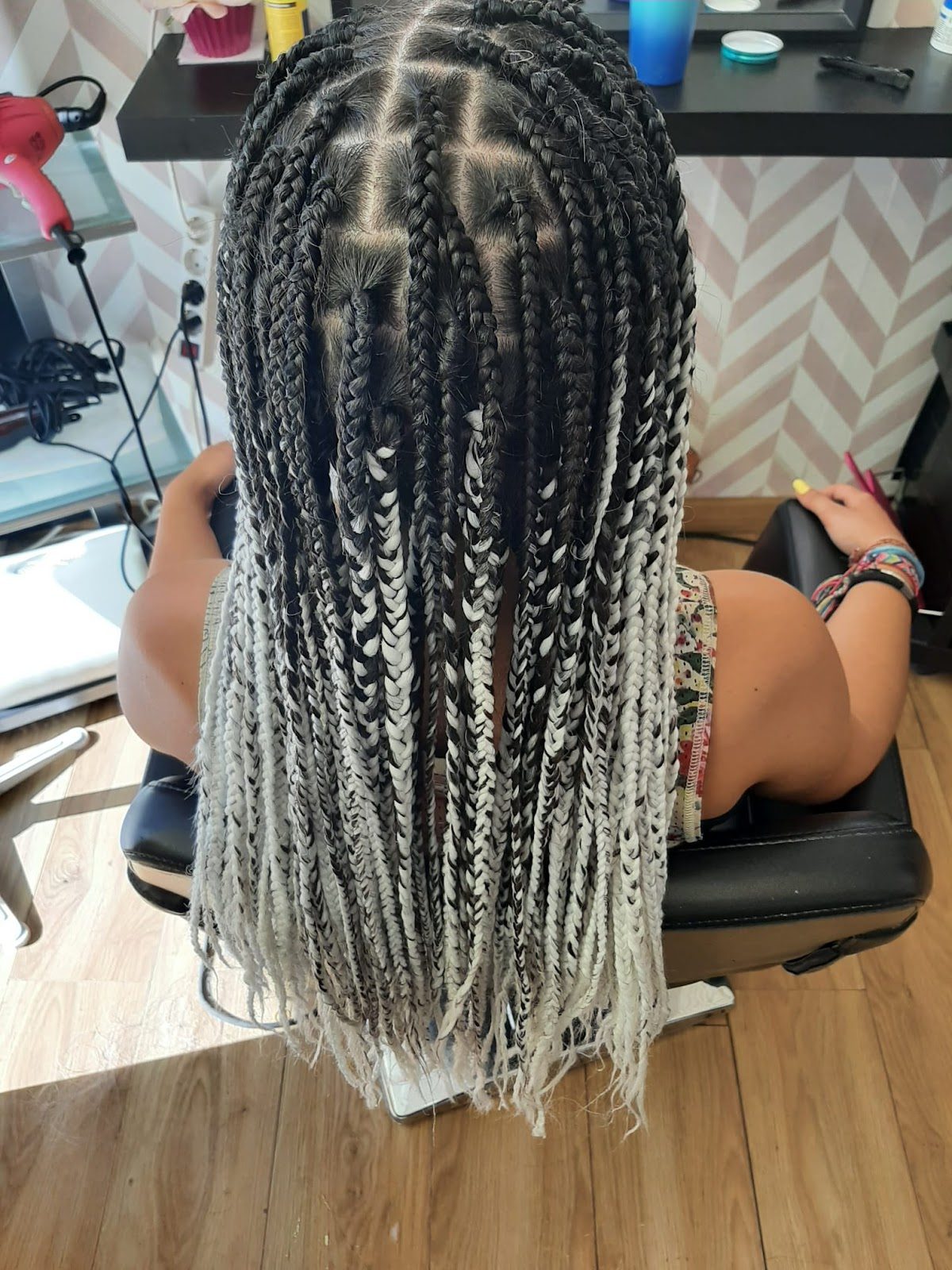 A client with long braided hair sits in a salon chair at BeautyShop, showcasing intricate black and white braids.