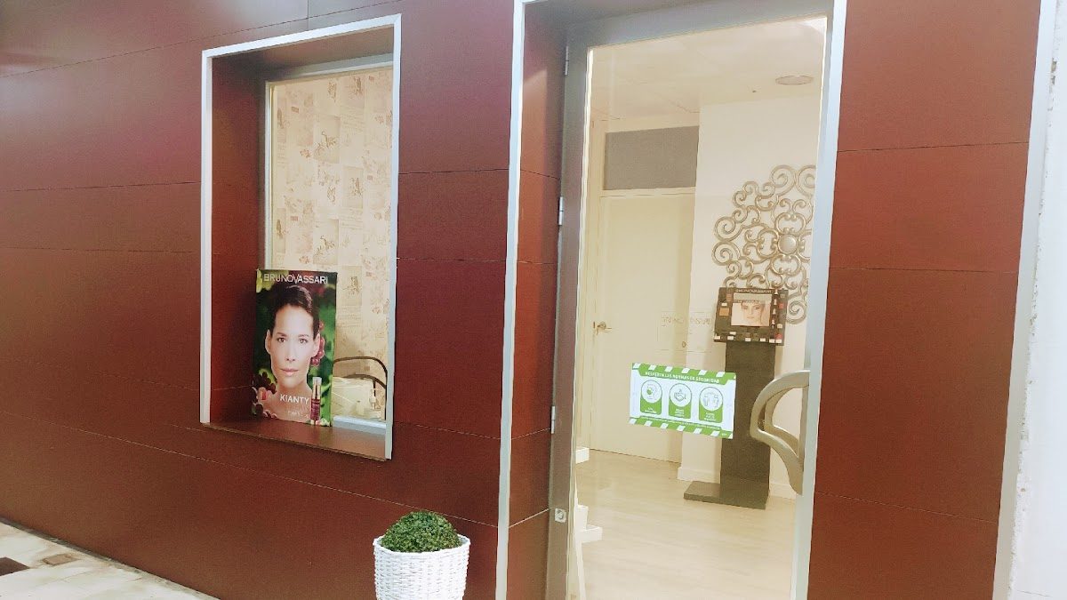 The entrance of Belleza - Solarium Eli features a modern design with a promotional poster and greenery.
