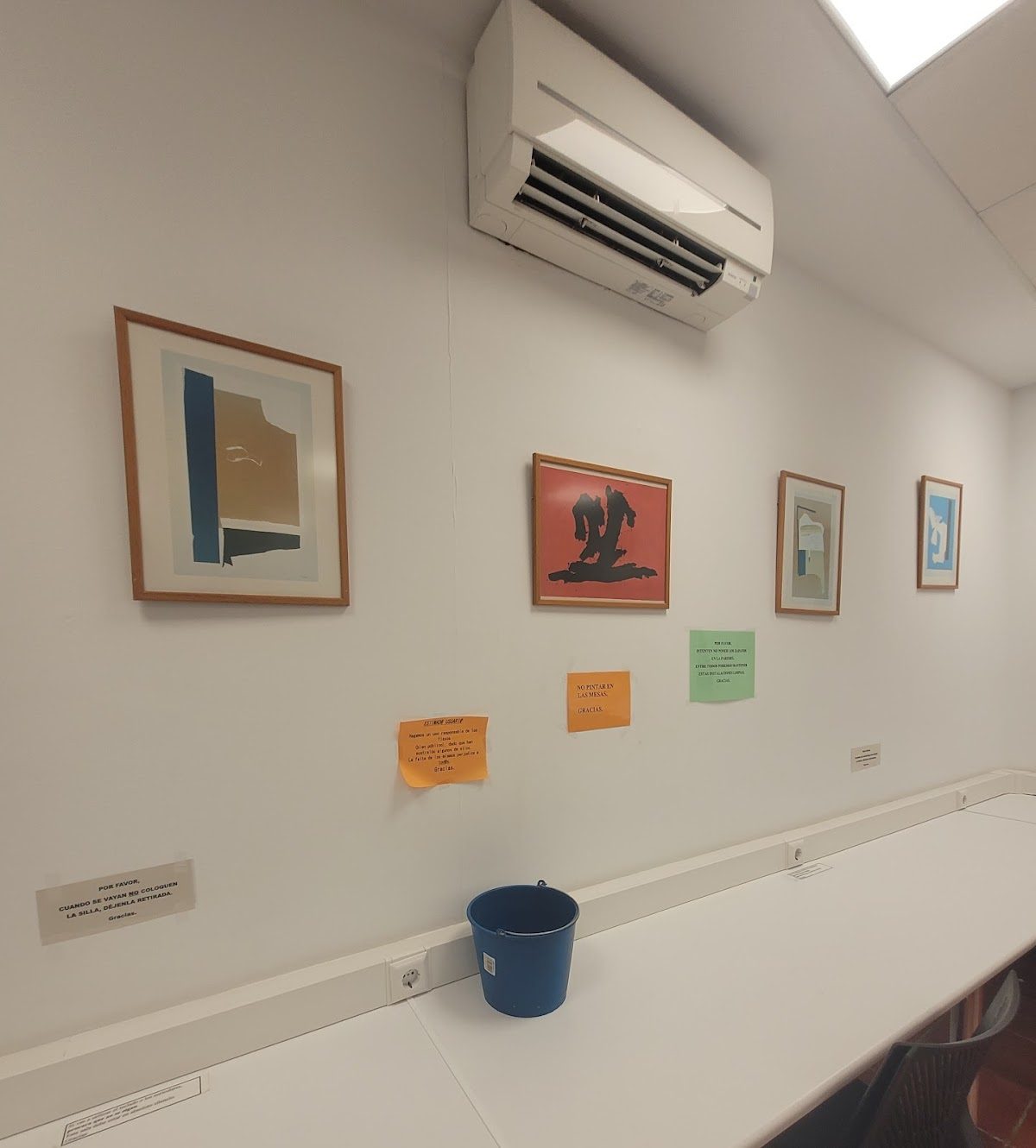 A bright study area at Biblioteca Municipal Entreculturas featuring framed artwork and colorful informational signs.