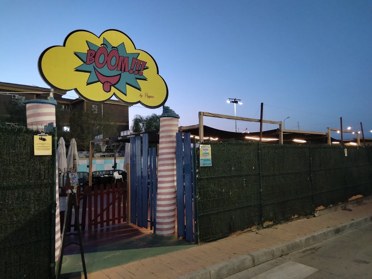 Colorful entrance to Boom by Poppins, featuring a playful sign and a fenced outdoor area.