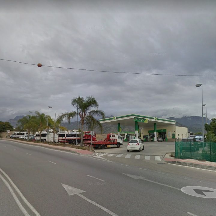 A bp gas station with palm trees and parked vehicles on a cloudy day in Nerja, Málaga.