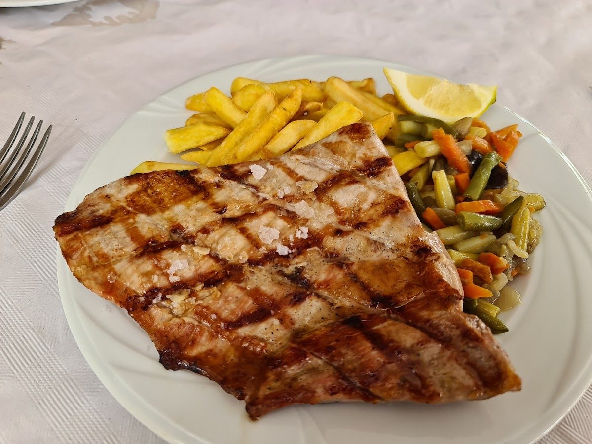 Grilled fish fillet served with fries and mixed vegetables at Café Bar Alcalá.