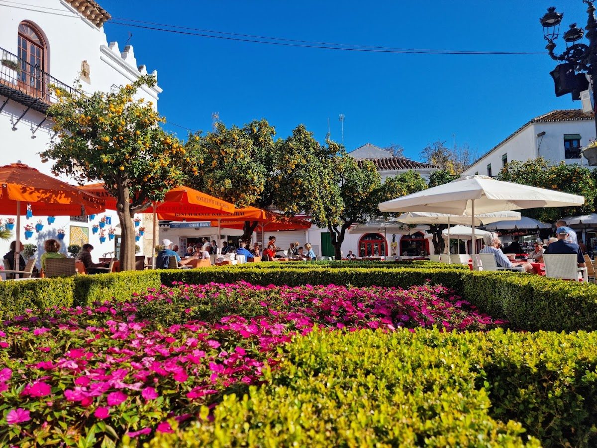 Flores coloridas y vegetación rodean las terrazas de los Cafés y Jardines en la Plaza de los Naranjos, Marbella.