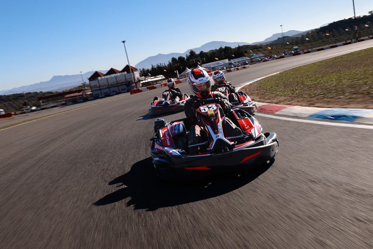 Carreras de karts en la pista del circuito de karts de Campillos, rodeado de montañas y cielos azules.