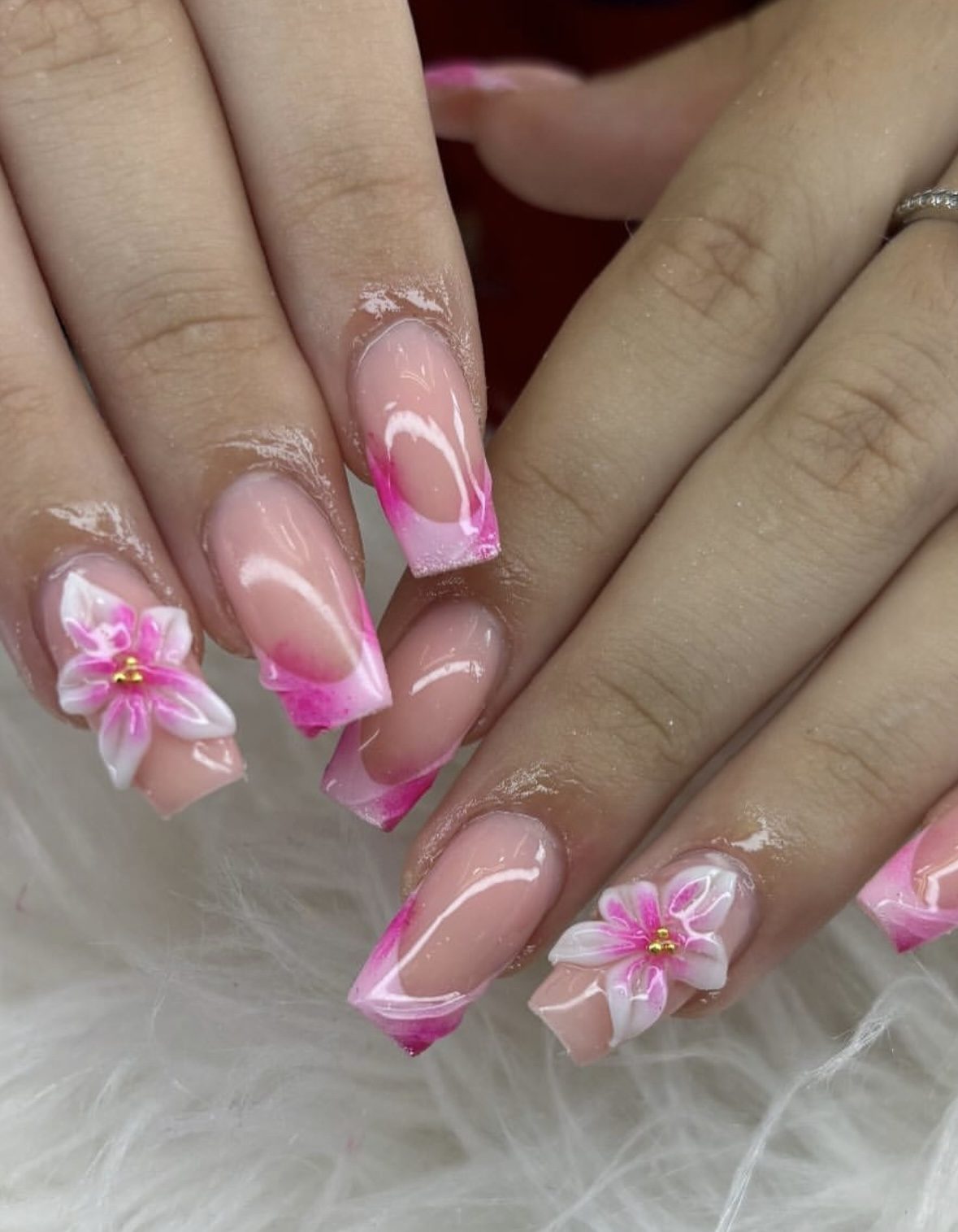 Elegant pink and white nail design with floral accents at Carmen Orejuela Salón de belleza.