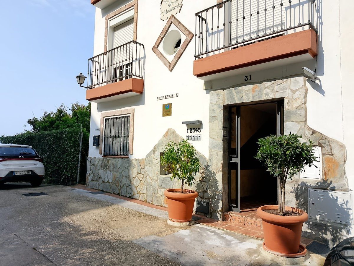 The entrance of Casa Rural Monteverde features stone walls, potted plants, and a welcoming door.