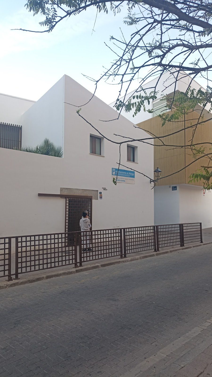 The Centro de Servicios Sociales del Distrito Centro features a modern white building with a wooden entrance gate.