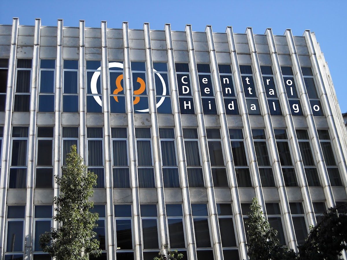 El exterior del Centro Dental Hidalgo presenta un edificio moderno con grandes ventanales y un logotipo prominente.