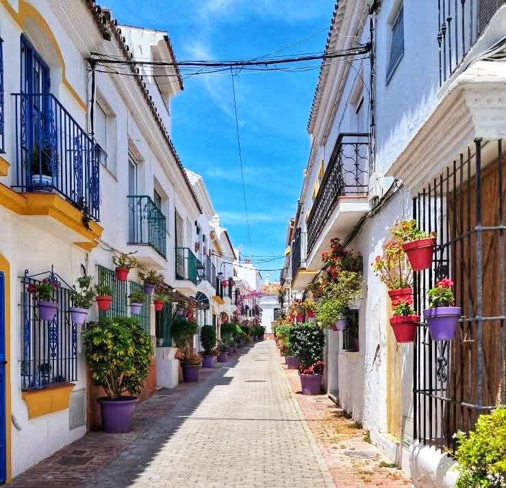 Encantadora callejuela en el Centro Histórico de Estepona, bordeada de coloridas macetas y edificios encalados.