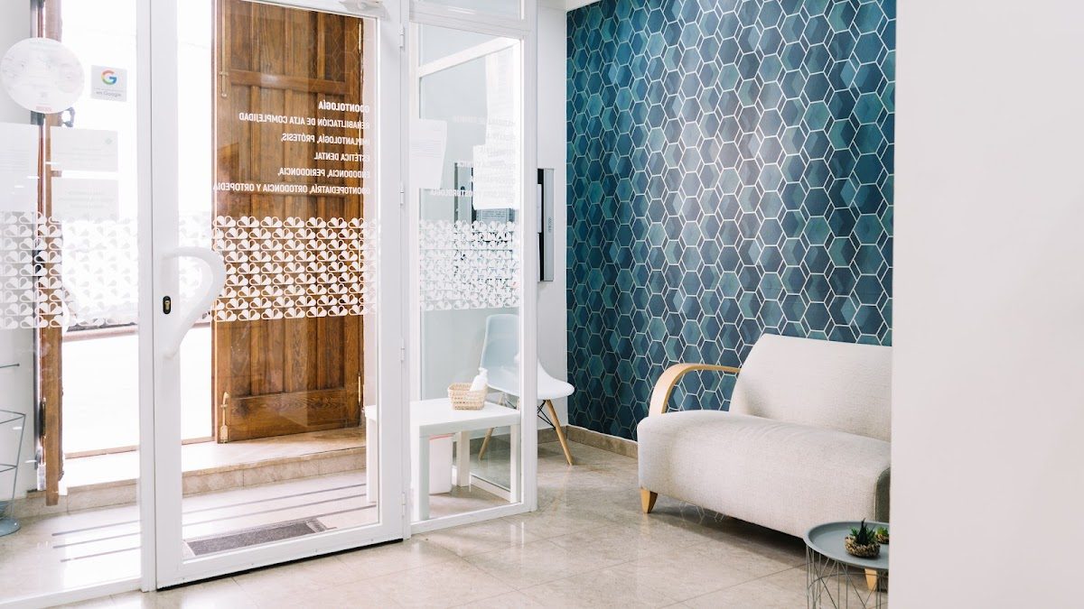 Moderna sala de espera del Centro Médico Antequera con pared de azulejos hexagonales y cómodos asientos.