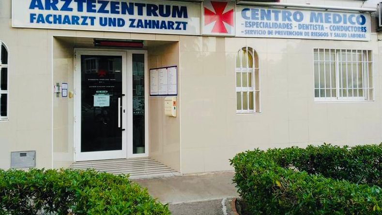 La entrada del Centro Médico Ärztezentrum Torrox Costa cuenta con una puerta de cristal y un letrero que indica que se ofrecen servicios dentales.