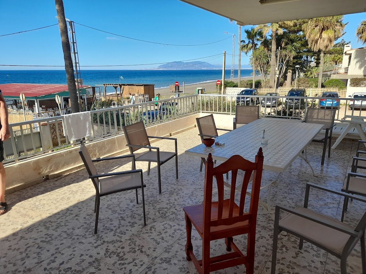 Zona de estar al aire libre con mesas y sillas con vistas a la playa en Chiringuito Aquí Mismo.