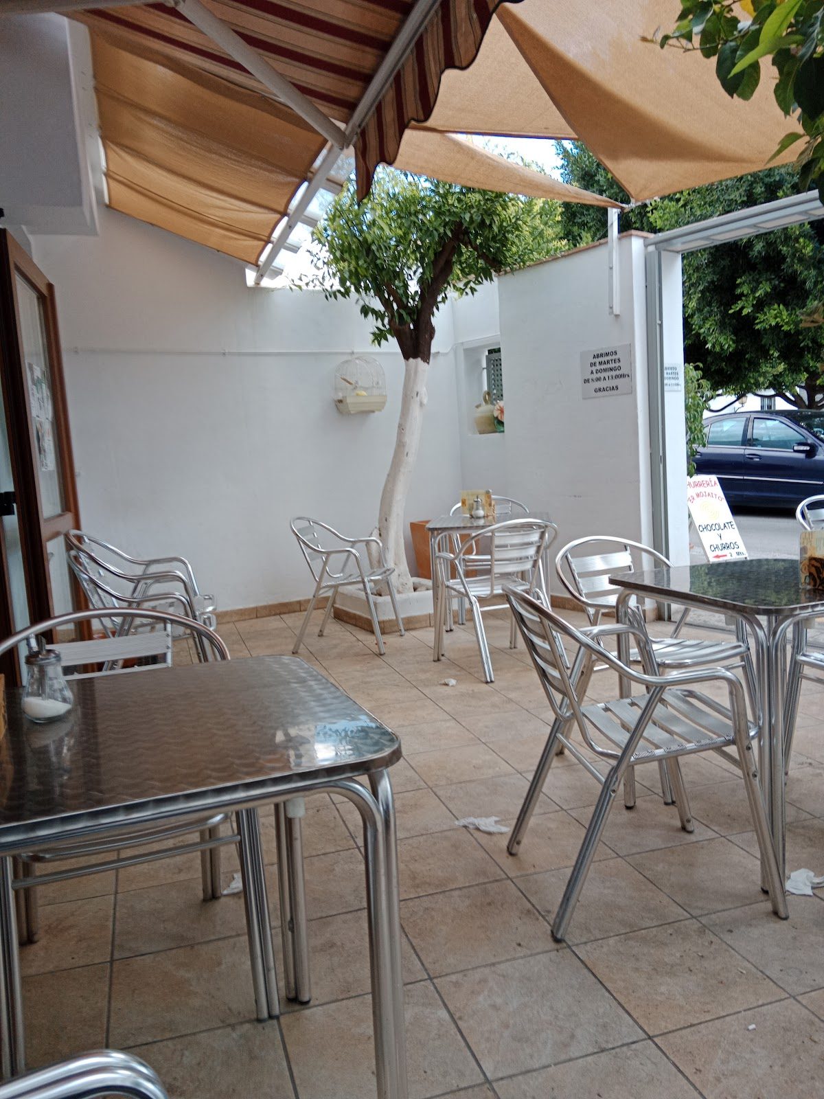 Outdoor seating area with metal tables and chairs at Churreria El Mojaito in Ojén.